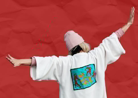 a woman with her back to us, arms outstretched. she's on a red background.