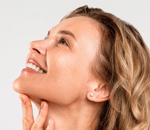 Woman looking up, touching her chin, showcasing a refined jawline.