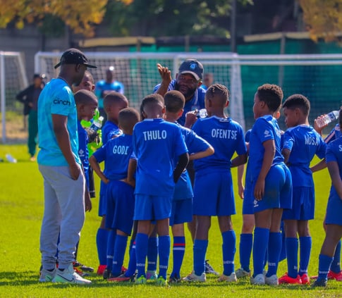 a group of young boy soccer players standing in a circle