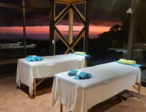 two massage beds in a room with a view of the ocean