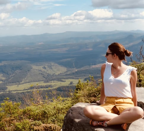 a woman sitting on a rock with a view of the mountains