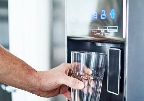 a person holding a glass of wine in front of a machine