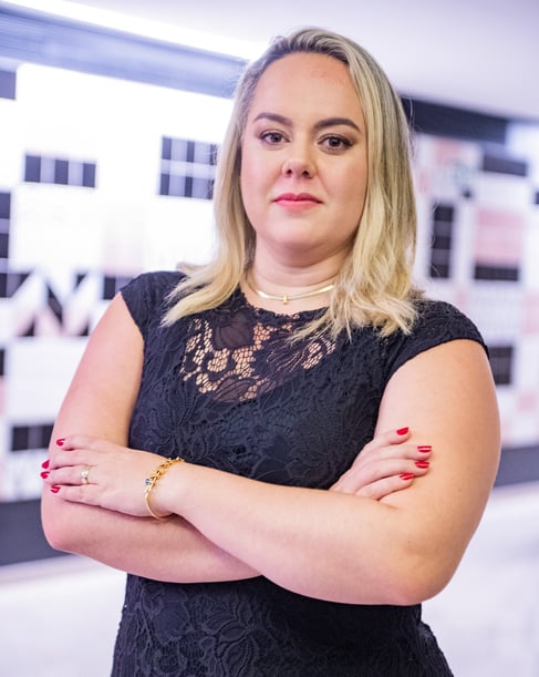 uma mulher loira de meia idade com vestido preto e esmalte vermelho nas unhas.