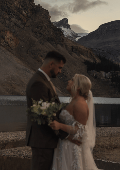 Eloping couple standing at the shore of bow lake in banff while watching the moon rise 