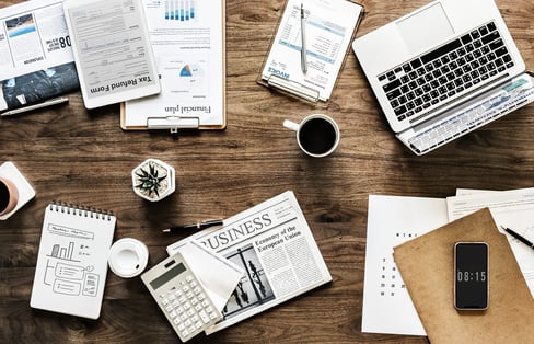 a desk with a laptop and diverse business documents