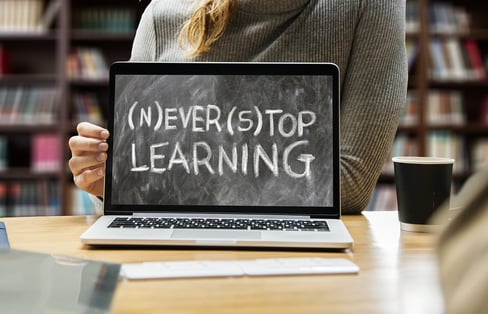 a woman showing a laptop computer screen saying never stop learning