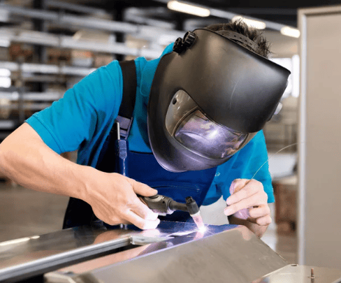 a man in a welding helmet welding a metal object
