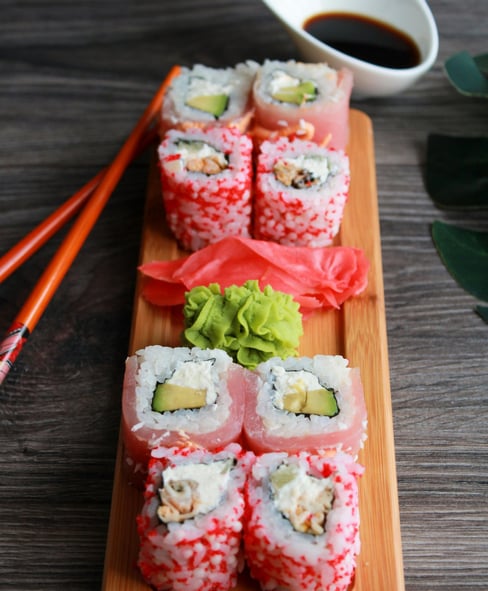 8 red Sushi rolls on a plate with wasabi