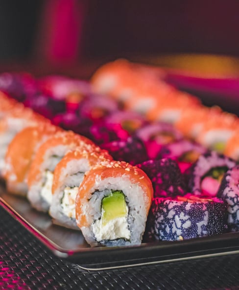 Multiple sushi rolls lined up on a tray