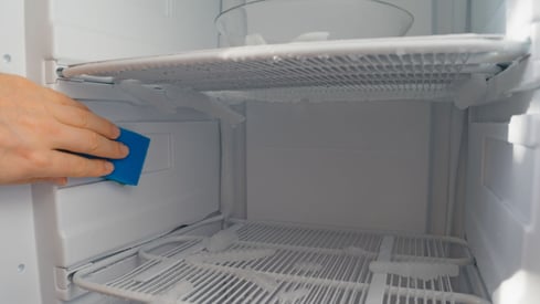 a person cleaning a refrigerator door with a sponge pad