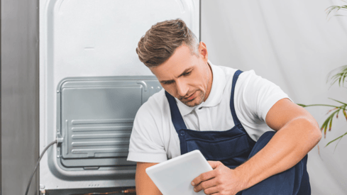 a man in a blue apron and a tablet computer