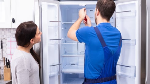 a man and woman standing in front of a refrigerator