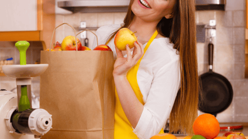 a woman holding a paper bag with apples and apples
