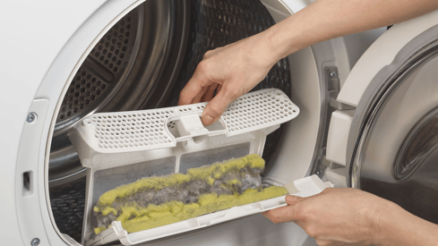 a person is putting a plastic container into a washing machine
