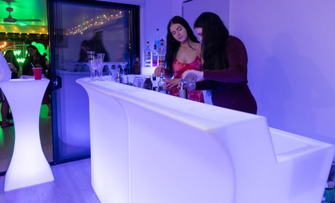 LED glow bar hire setup in Redlands for vow renewal, featuring cocktail table and two bartenders mixing drinks