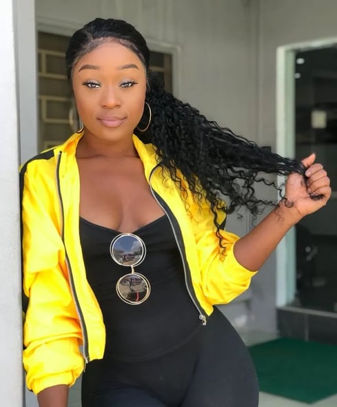 Efia Odo in a yellow jacket with a black inner dress with sunglasses.