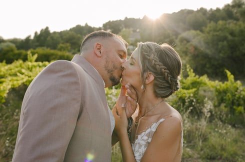 un couple jeune marié qui s'embrasse au coucher du soleil au milieu des vignes