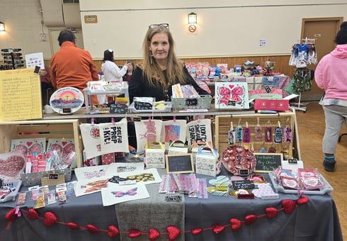 a woman standing behind a table with a table with a table cloth