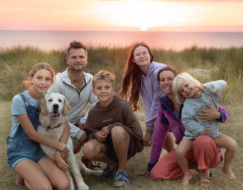 Famille nomade (2 adultes, 4 enfants, chien) voyageant en van sous un coucher de soleil. Paysage pai