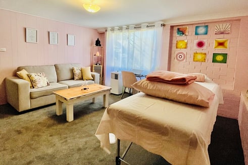 healing room with table, couch and massage table in pink