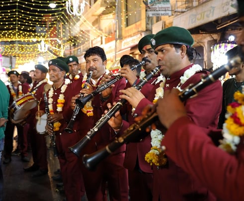 Crew members of the Manohar Brass Band playing clarinet, shehnai, and thap dhol instruments during a traditional performance.