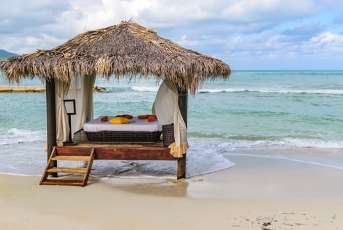 a bed with a canopy over it on the beach next to water