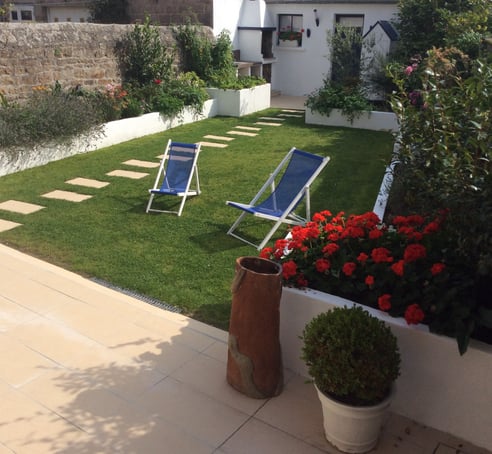 Jardin aménagé avec bordures maçonnées, pelouse soignée et dalles décoratives