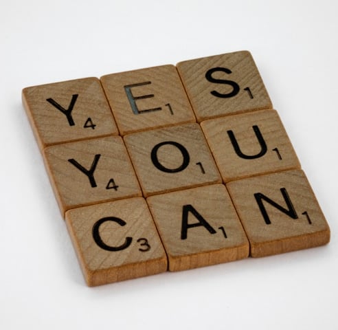 9 wooden Scrabble tiles laid in a square. Spell Yes You Can