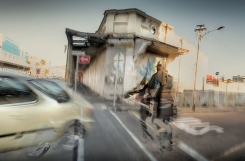 Energetic abstract photo of a cyclist, car, and street corner in Salt River, Cape Town, blending urban textures and movement.