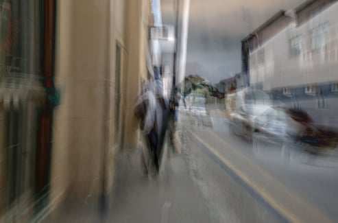 Abstract Cape Town street photograph showing a layered impression of a woman in a headscarf walking past cars and buildings
