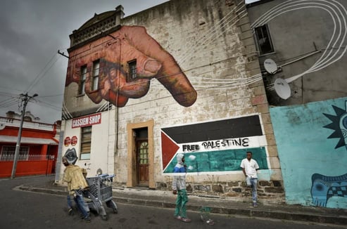 Fine art urban photograph capturing layered graffiti and street life with a large Free Palestine mural in Cape Town