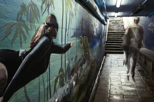 Fine art photograph by Martin Osner showing a blurred figure walking through the famous Kalk Bay subway with a wall mural