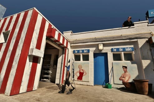 Colourful fine art photograph by Martin Osner showing red and white striped walls and vintage seaside dressing room signs