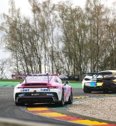 Porsche 911 gt3 rosa e bianca in curva durante gara