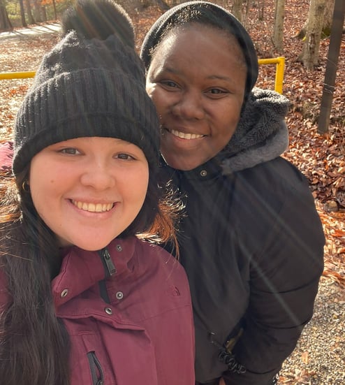 two women standing next to each other. one is in a burgundy jacket and the other is in a black one. 