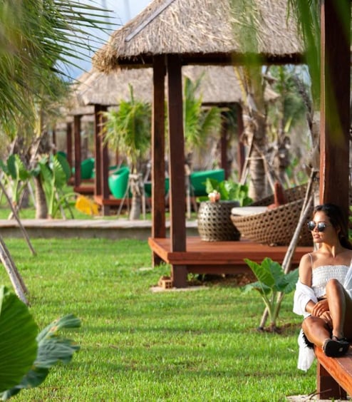 a woman sitting on a bench in a tropical setting