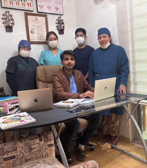 a group of people standing around a table with a laptop