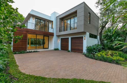 a brick driveway to a square looking custom designed luxury home