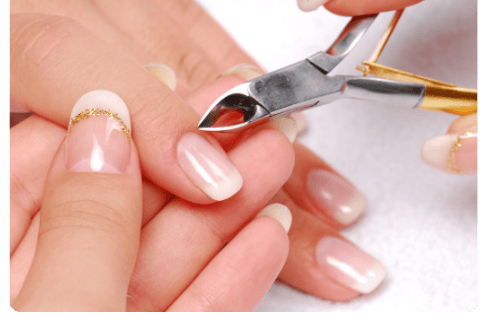mãos de uma mulher com uma manicure bem cuidada com um alicate cutícula afiado