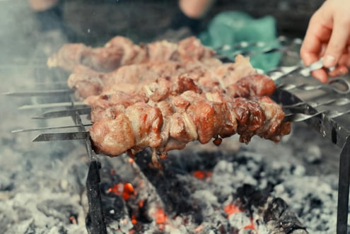 a person is cooking on a grill with meat and vegetables