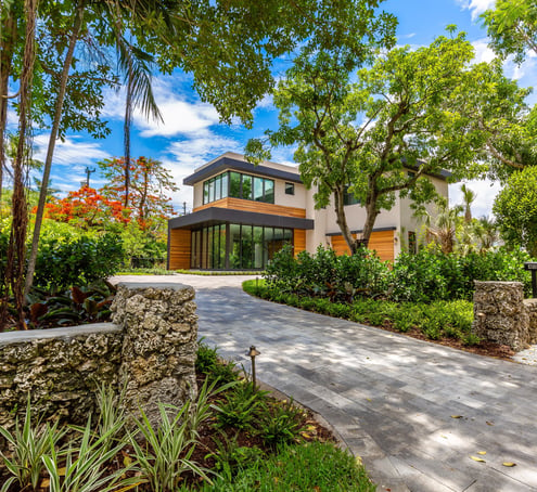 brick driveway leading to a vibrant front yard of a custom built luxury home