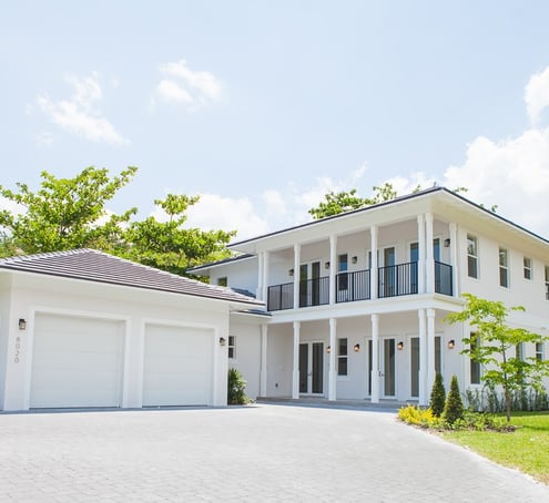 a white luxury home with a large driveway shown and a two door garage