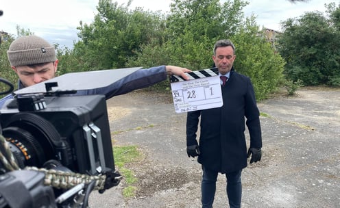 James Yeates Actor on set in front of a clapper board, highlighting professional film and television