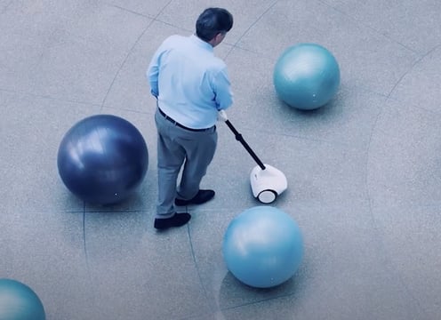Image of a middle aged man navigating large, round bollards with the Glide device.