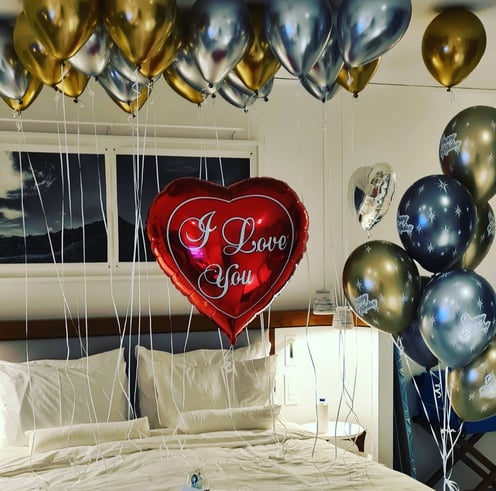 Romantic surprise room setup with heart-shaped balloons for an anniversary celebration.