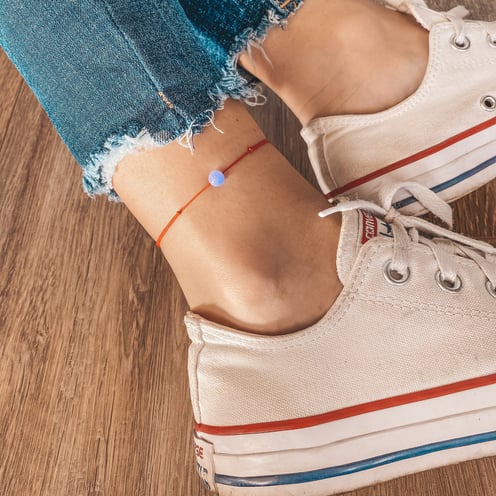 a person wearing a bracelet with a small bead on it