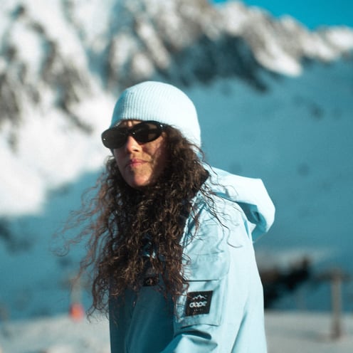 Une femme à la montagne habillé d'une veste bleue de la marque DOPE.