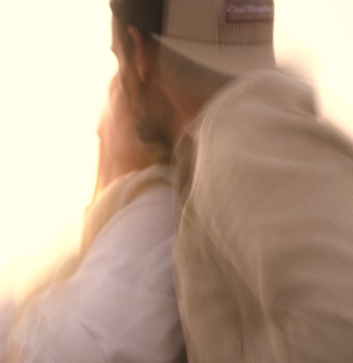 Photo artistique d'un couple habillés en beige à la lumière d'un coucher de soleil.
