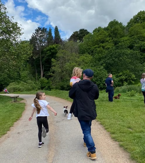 Rob Hamilton carrying his granddaughter in the park with his dog