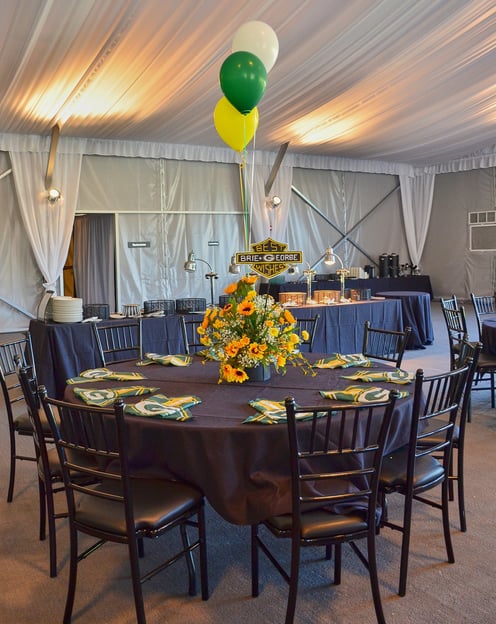 a table with green, yellow and white balloons and sunflowers and Green Bay Packers napkins